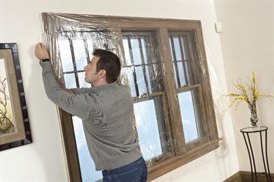 Man insulating windows with film